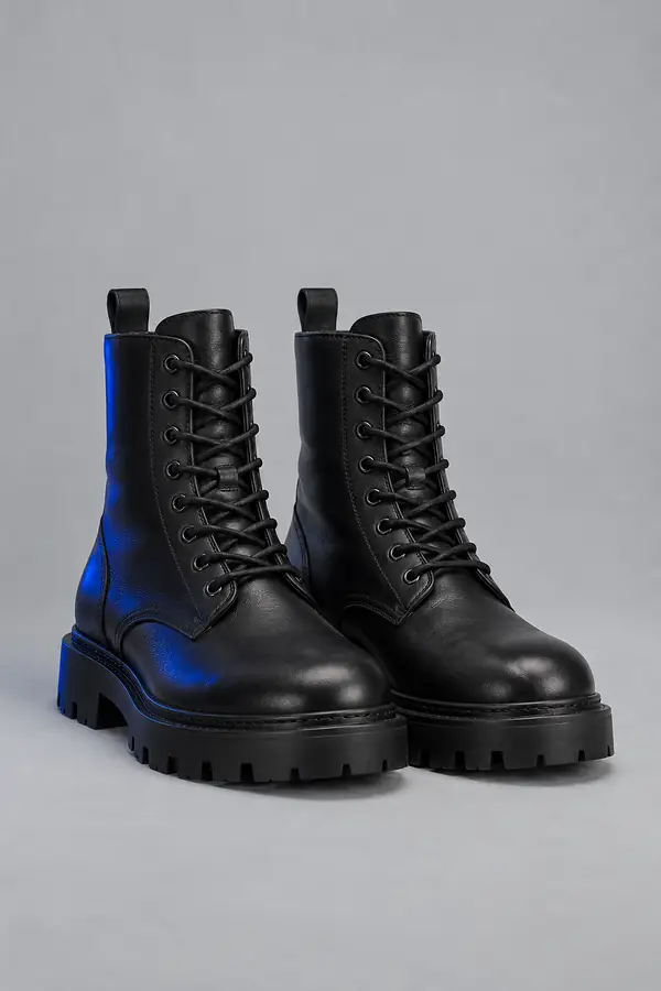 Pair of plain black leather boots on a light grey backdrop